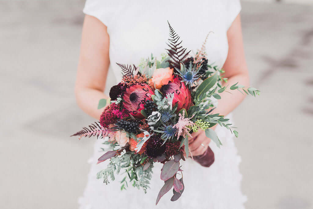 Brautstrauß "Skyler" mit Brombeerblüten und exotischer Protea in bunten Farbtönen.