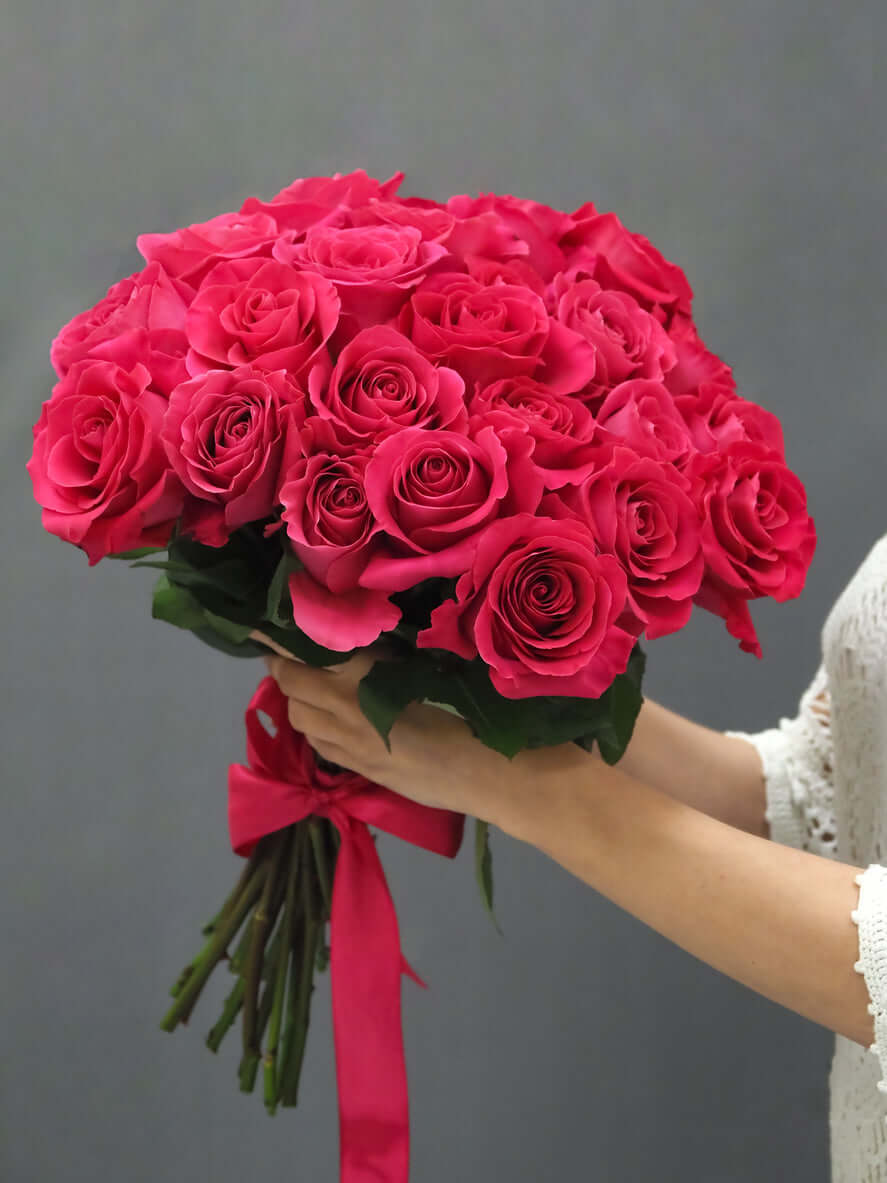 Rosenstrauß "Pink Floyd" mit leuchtend pinken Rosen, kunstvoll gebunden und präsentiert von einer Hand.